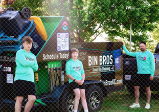 Two Liberty teen brothers in matching Bin Bros KC hoodies with their dad, standing by the trash bin cleaning trailer and equipment